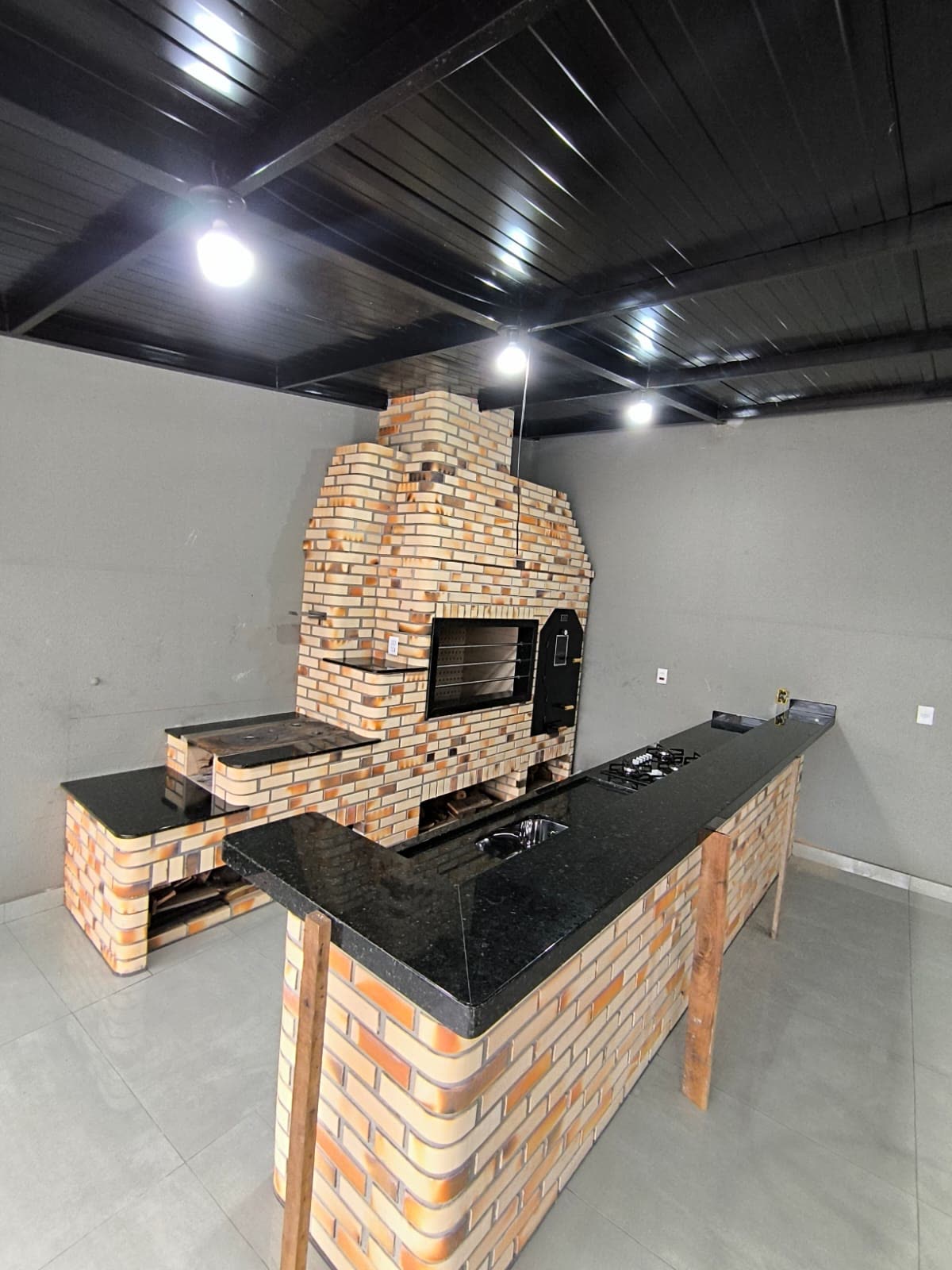 Área gourmet com churrasqueira e bancada em granito preto